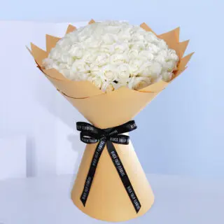 White rose bouquet in a brown wrap tied with black ribbon.