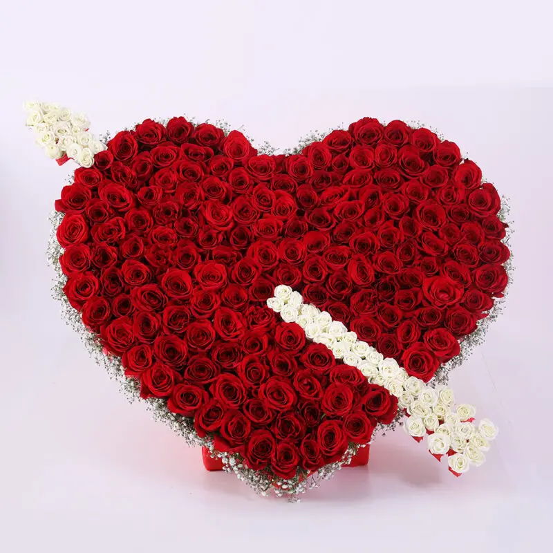 01 A heart-shaped arrangement of red roses with a white arrow made of roses and baby's breath piercing through it.