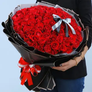 Valentines Day Home 71 A woman with a stunning bouquet of 100 red roses, highlighting the flowers' vivid color and abundant petals.