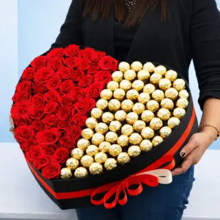 Valentines Day Home 59 A woman holds a heart-shaped box filled with Ferrero chocolates and by 50 red roses, symbolizing love and affection.