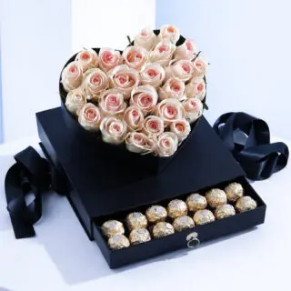 Light pink roses within a heart shape black box and Ferrero chocolates under the box.