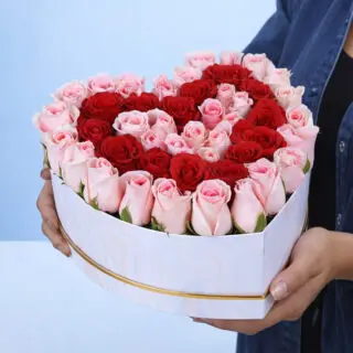 Valentines Day Home 58 A woman holds a heart-shaped box filled with vibrant roses, symbolizing love and affection, titled Precious Heart In A Box.