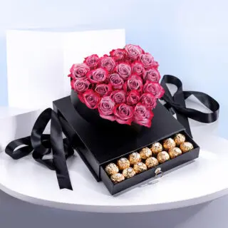 A luxurious gift box featuring a heart-shaped arrangement of pink roses and a drawer filled with chocolates.