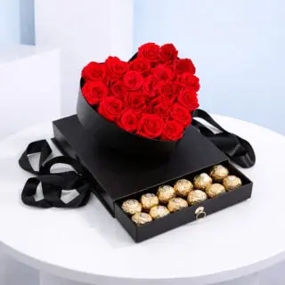 A heart-shaped black box filled with red roses, featuring a compartment for Ferrero Rocher chocolates.