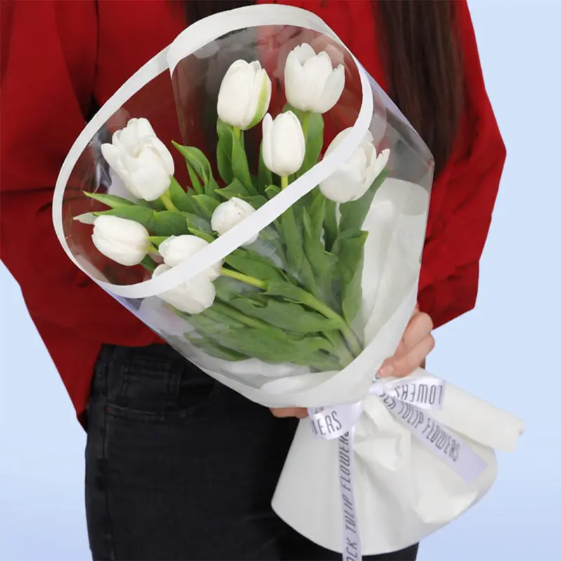 white-tulips–10-stems-2026 a bouquet of white tulips wrapped in clear plastic and white paper.