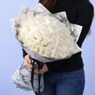 Elegant bouquet of 50 white roses with lush greenery, wrapped in premium paper and tied with a satin ribbon.