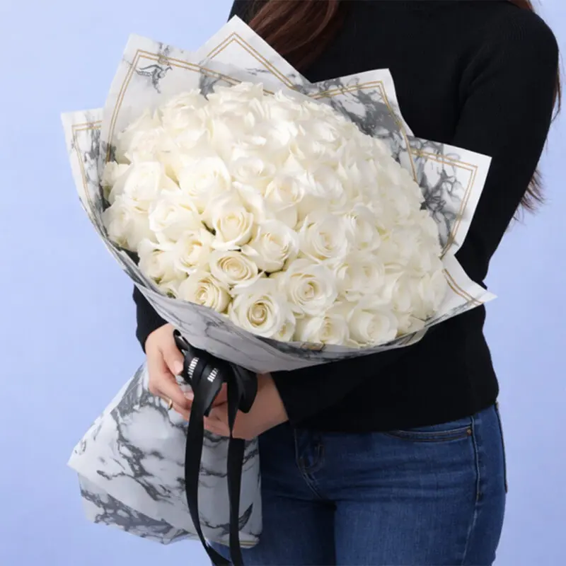 whitening-rose-bouquet-2026 Elegant bouquet of 50 white roses with lush greenery, wrapped in premium paper and tied with a satin ribbon.
