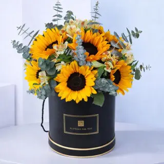 A vibrant floral arrangement of sunflowers, alstroemerias, and eucalyptus in a charming box, perfect for brightening any day.