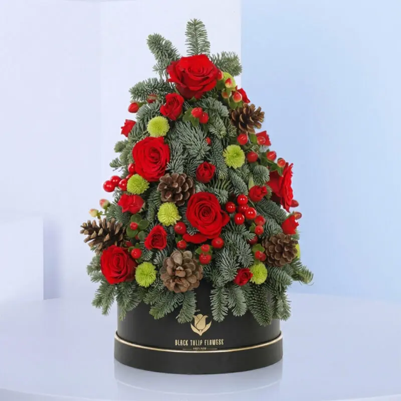 Mini-Luscious-Tree-01-12-05-25 A delightful mini tree in a black box featuring pine cones, red roses, and green chrysanthemums, ideal for Christmas presents.