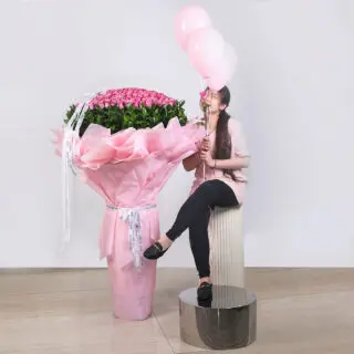 A large bouquet of 300 purple roses, elegantly wrapped in pink paper and presented on a grand stand.