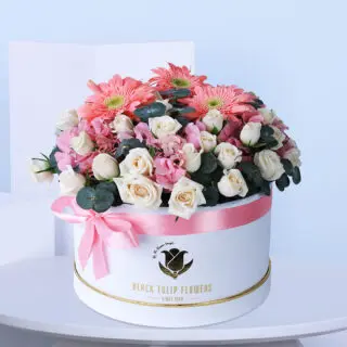 Close-up view of a beautiful combination of red and white roses arranged in a white box tied with a pink ribbon.
