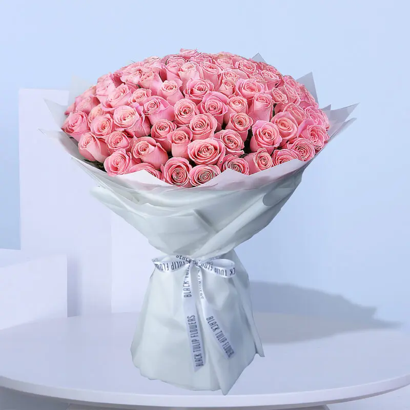 02 A large bouquet of light pink roses wrapped in white paper with white ribbons.