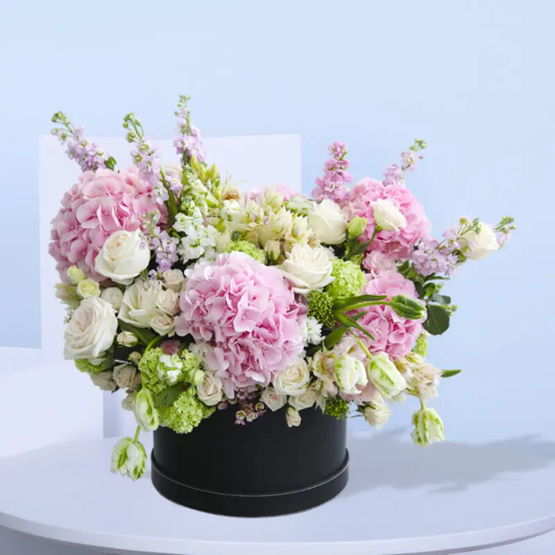 Beautiful arrangement of pink hydrangeas, white roses, and other pastel flowers in a black box.
