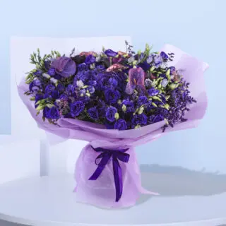 Beautiful bouquet of purple flowers arranged in a lavender wrap, elegantly tied with a matching purple ribbon.