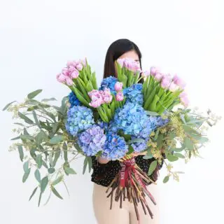 a large bouquet of pink tulips, blue hydrangeas, and eucalyptus.