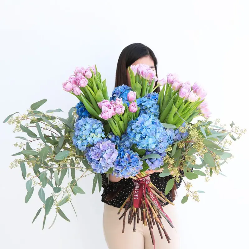 Blue and Purple Tandem (1) a large bouquet of pink tulips, blue hydrangeas, and eucalyptus.