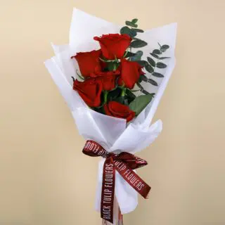 Charming bouquet of 6 red roses paired with fresh eucalyptus, elegantly wrapped in white and finished with a maroon ribbon.