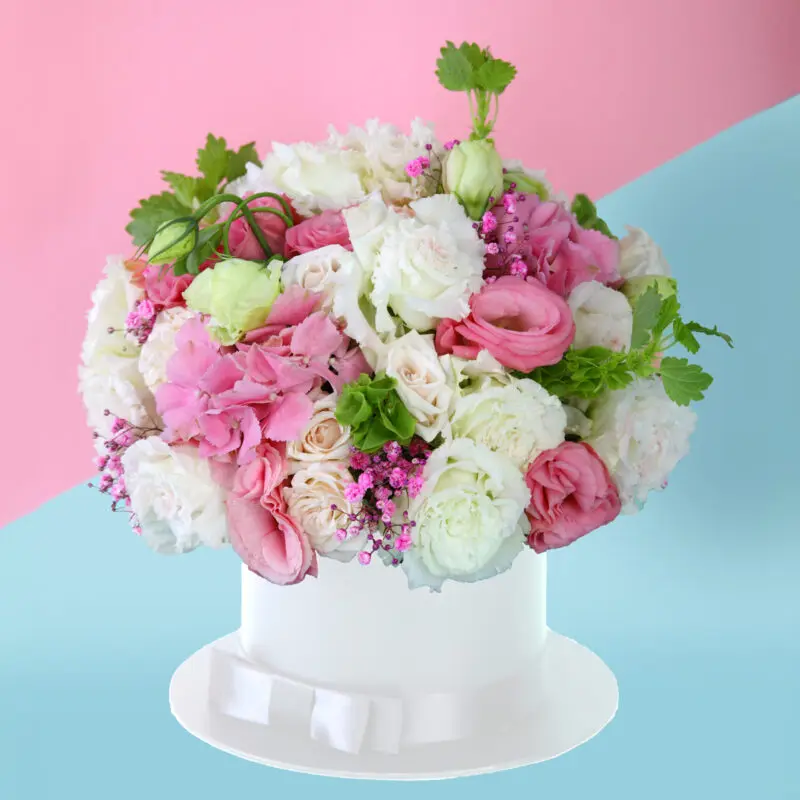 Prodcut - front Elegant arrangement of white and pink flowers with lush greenery in a chic white hat box.