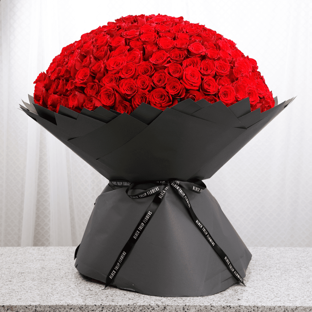 A huge bouquet of red roses beautifully wrapped in a sleek black wrap.