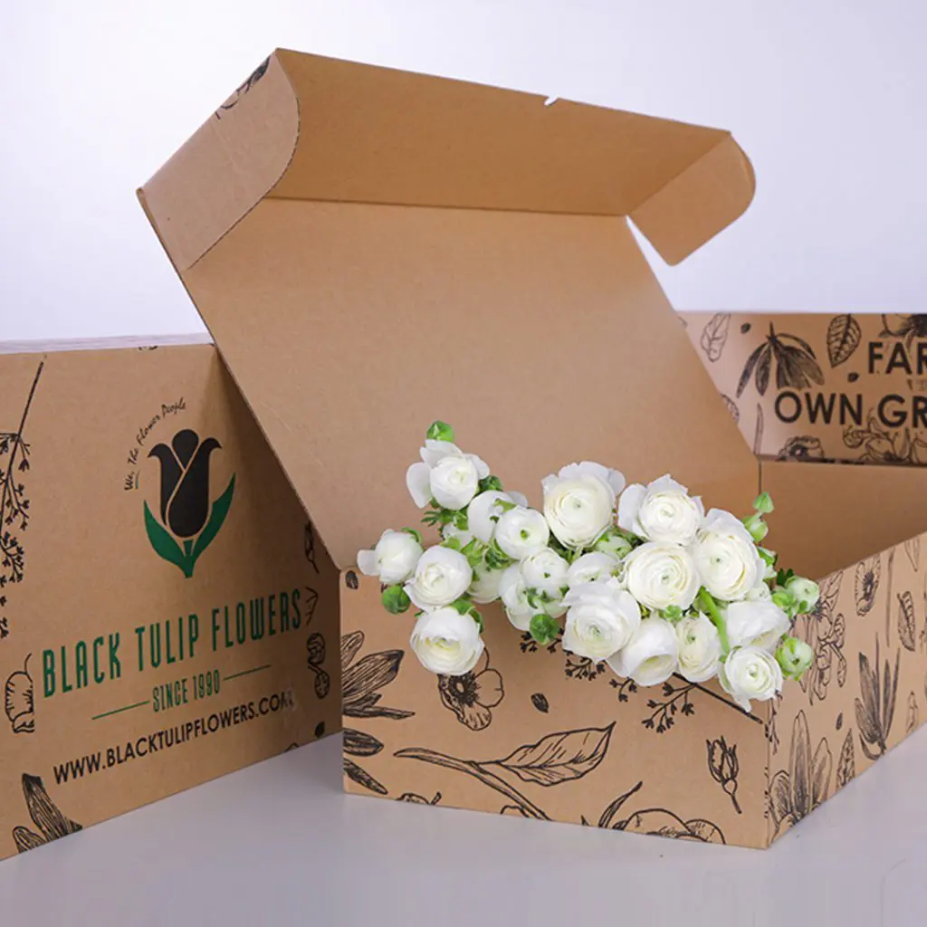 Ranunculus White (2) A cardboard box filled with a bunch of white Ranunculus flowers, showcasing their delicate petals and vibrant beauty.