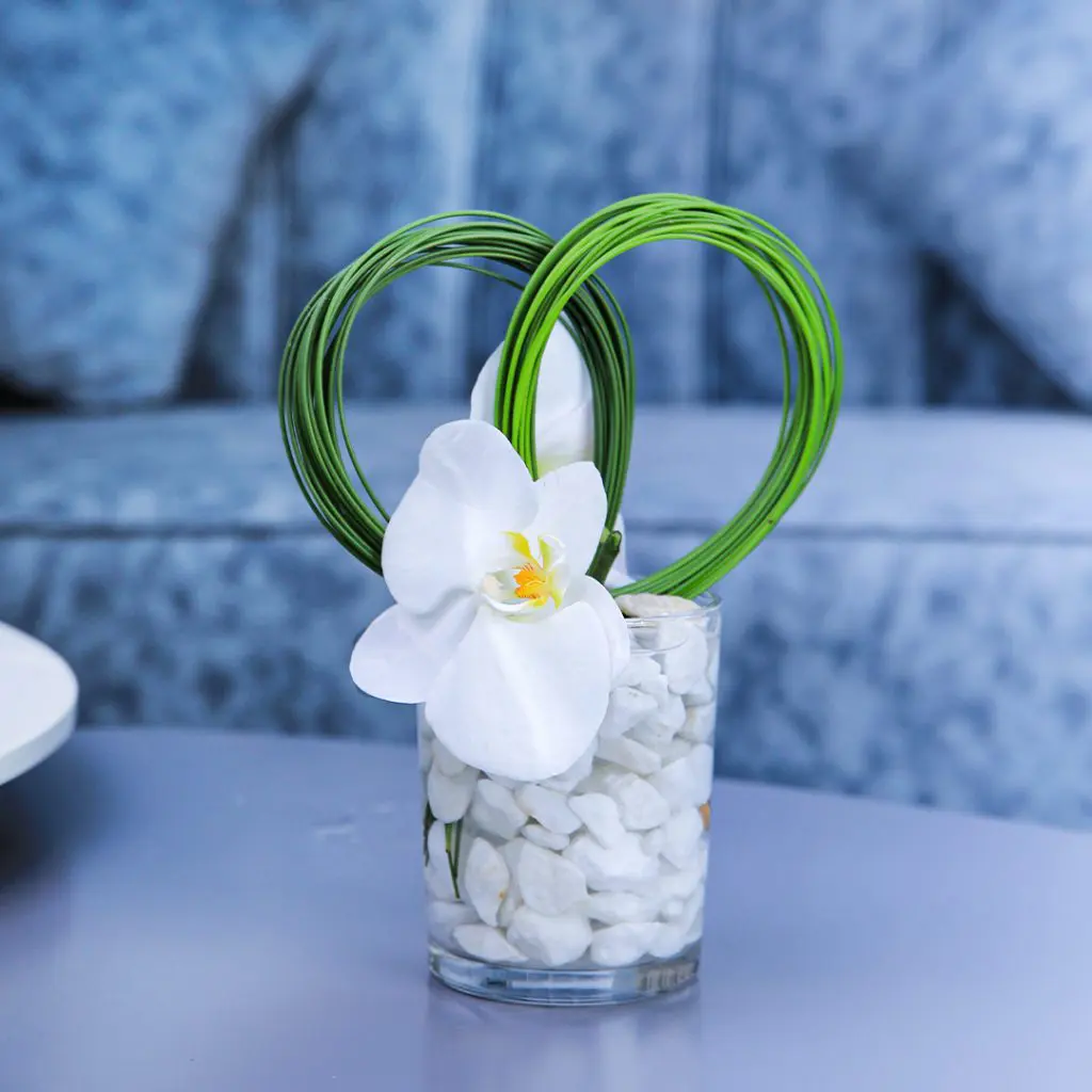 Centerpiece made with of Phalaenopsis White flower with white pebbles and green leaves