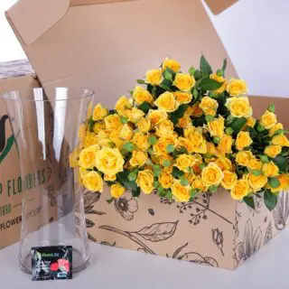A bunch of yellow roses in a glass vase, accompanied by flower food to keep them fresh and vibrant.