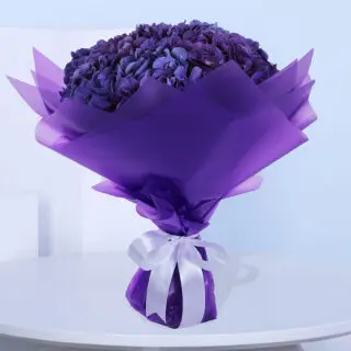 A bouquet of purple Hydrangeas in a luxury purple wrap tied with a white ribbon.