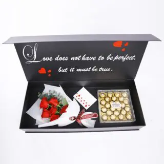 A Valentine gift box with a unique love quote contains red roses, eucalyptus, and a box of Ferrero Rocher chocolates.