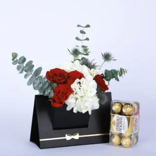 Red roses and white hydrangeas, accented with eucalyptus leaves in a black box with a bow, with Ferrero Rocher.