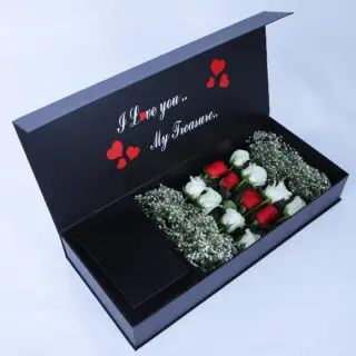 A black gift box with red and white roses arranged with gypsophila and a message "I love you. My Treasure.