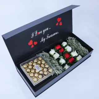 Detailed view of 12 roses and gypsophila in a black box with Ferrero chocolates and a love message sticker.