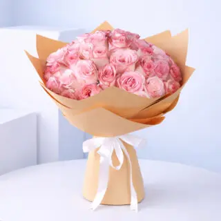 A beautiful arrangement of 50 pink roses, delicately wrapped in brown paper with a white ribbon.