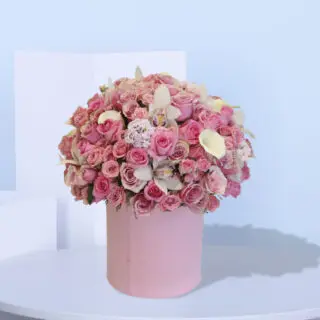 A large pink box filled with pink roses, white calla lilies, and white orchids.