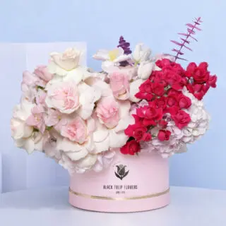 A beautiful "Pink Box" filled with light pink roses, dark pink spray roses, pink tulips, pink hydrangeas, and eucalyptus.