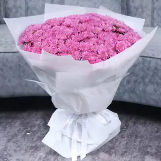 large bouquet of pink chrysanthemums wrapped in white paper.