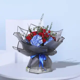 Stunning floral gift of red roses and blue hydrangeas, wrapped in black paper with a blue ribbon