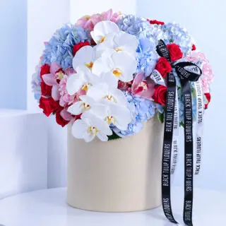 A flower box featuring 10 blue hydrangeas, 5 pink hydrangeas, 40 dark pink roses, and 2 orchid stems in white and pink.