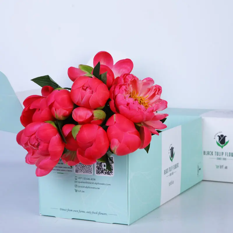 02 A bouquet of bright pink peonies in a light blue box with the Black Tulip Flowers logo.