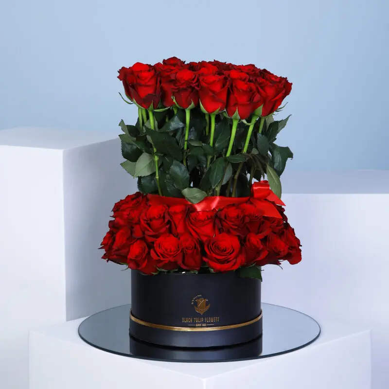 01 A stunning two-tier arrangement of 70 red roses in a elegant round black box.