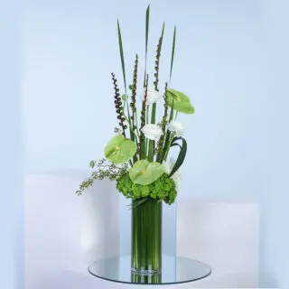 Tall green and white floral arrangement in a glass vase