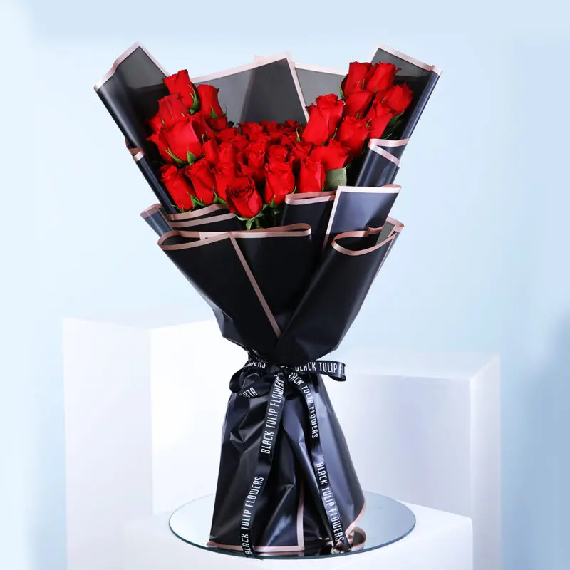 01 A beautiful bouquet of red roses wrapped in elegant black and gold paper.