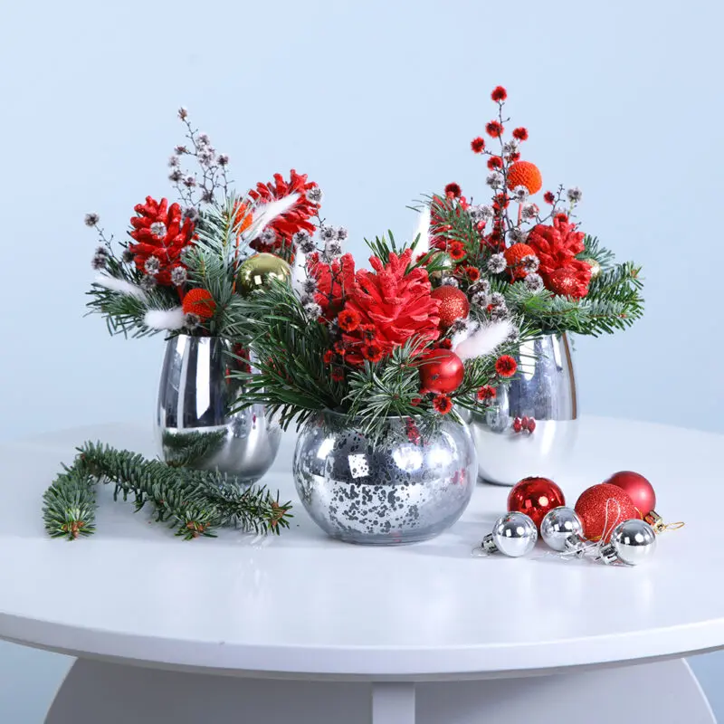 01 A trio of silver vases filled with vibrant Christmas flowers and decorative elements, enhancing the festive atmosphere.