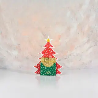 A festive chocolate shaped like a Christmas tree, adorned in vibrant red and golden colours, evoking holiday cheer.