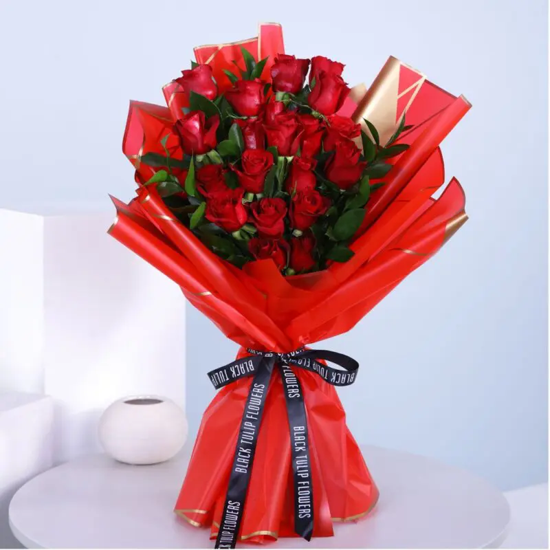 BTF_UAE_RED_01 A bouquet of a dozen red roses wrapped in red tied with a black ribbon.
