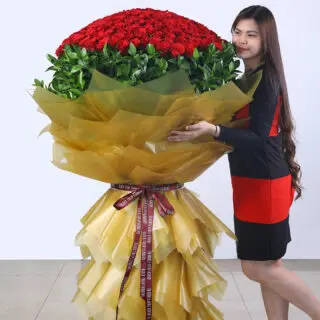 A large bouquet of 300 red roses, elegantly wrapped in gold paper and presented on a grand stand.