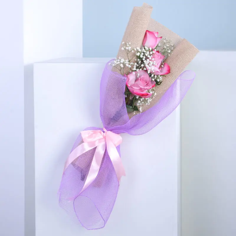 01 A bouquet of pink roses with a purple ribbon.