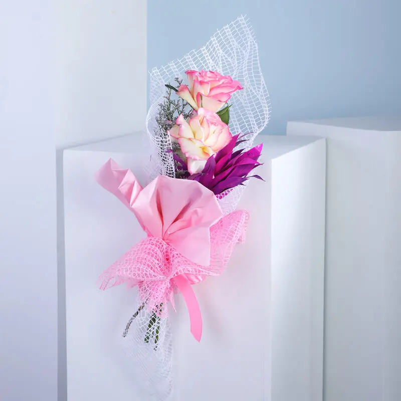 01 Bouquet of pink and yellow roses with purple flower accent.