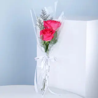 A bouquet of pink roses wrapped in clear plastic cellophane paper.