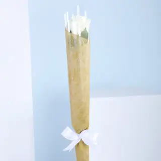 A bouquet of a single white roses wrapped in brown paper with a white ribbon.