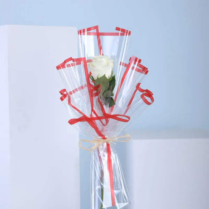 01 A single white rose in clear wrapping with red ribbons.
